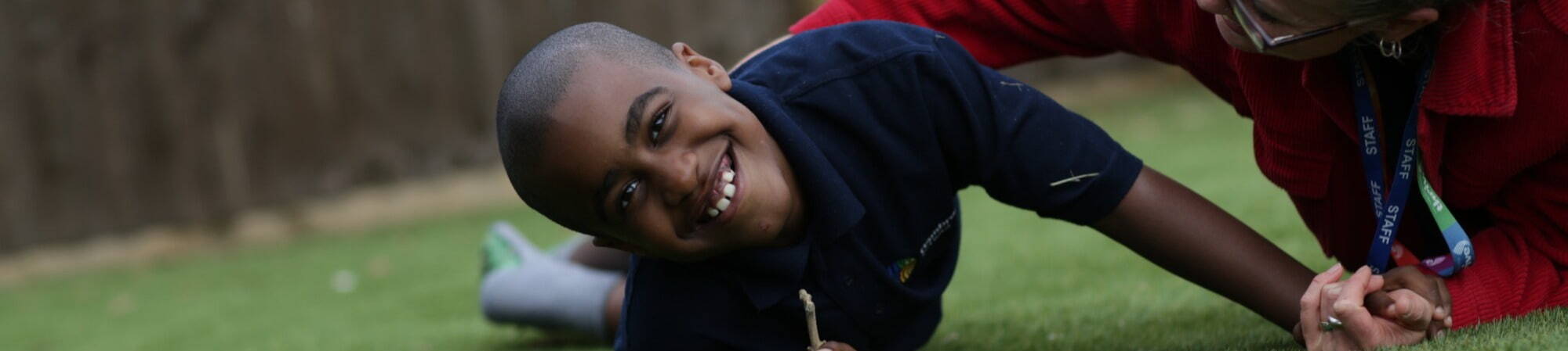 Happy school boy, rolling on grass